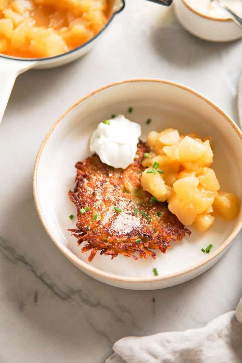 a plate with a potato pancake, homemade applesauce and sour cream dip