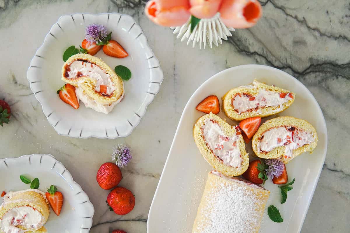 a platter and some plates with slices of strawberry sponge cake