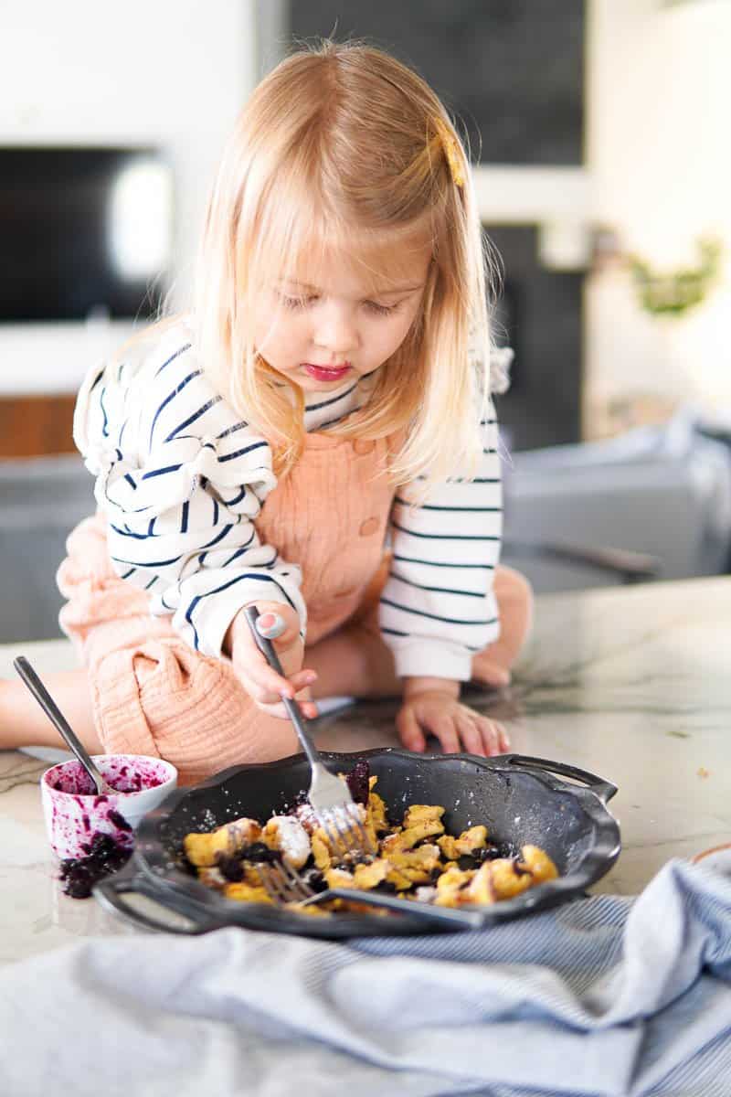 child eating kaiserschmarrn out of the skillet