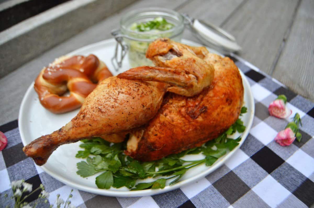 roasted Oktoberfest chicken on a plate with salad and pretzel