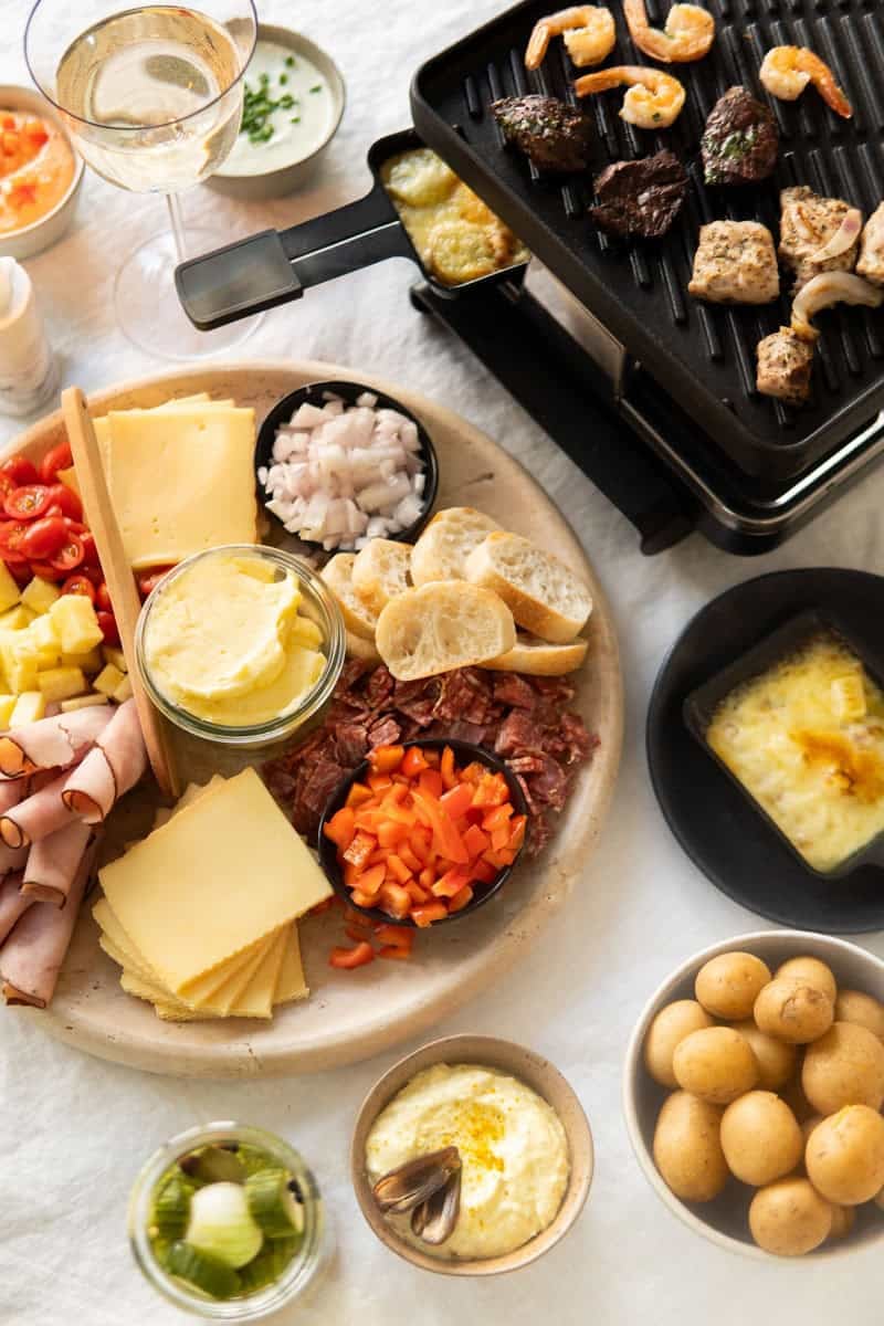 Raclette toppings on a platter with Raclette grill next to it.