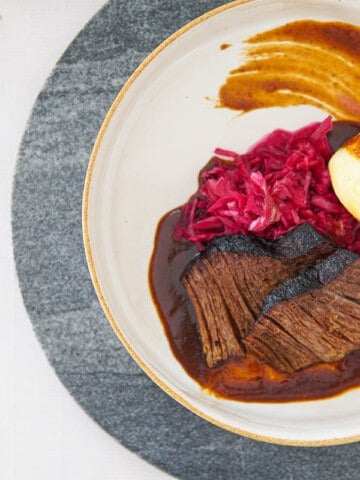 German beef pot roast on plate with potato dumplings and red cabbage