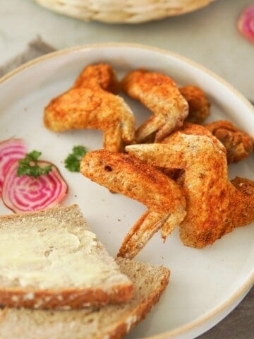 plate of fried chicken wings and a slice of bread
