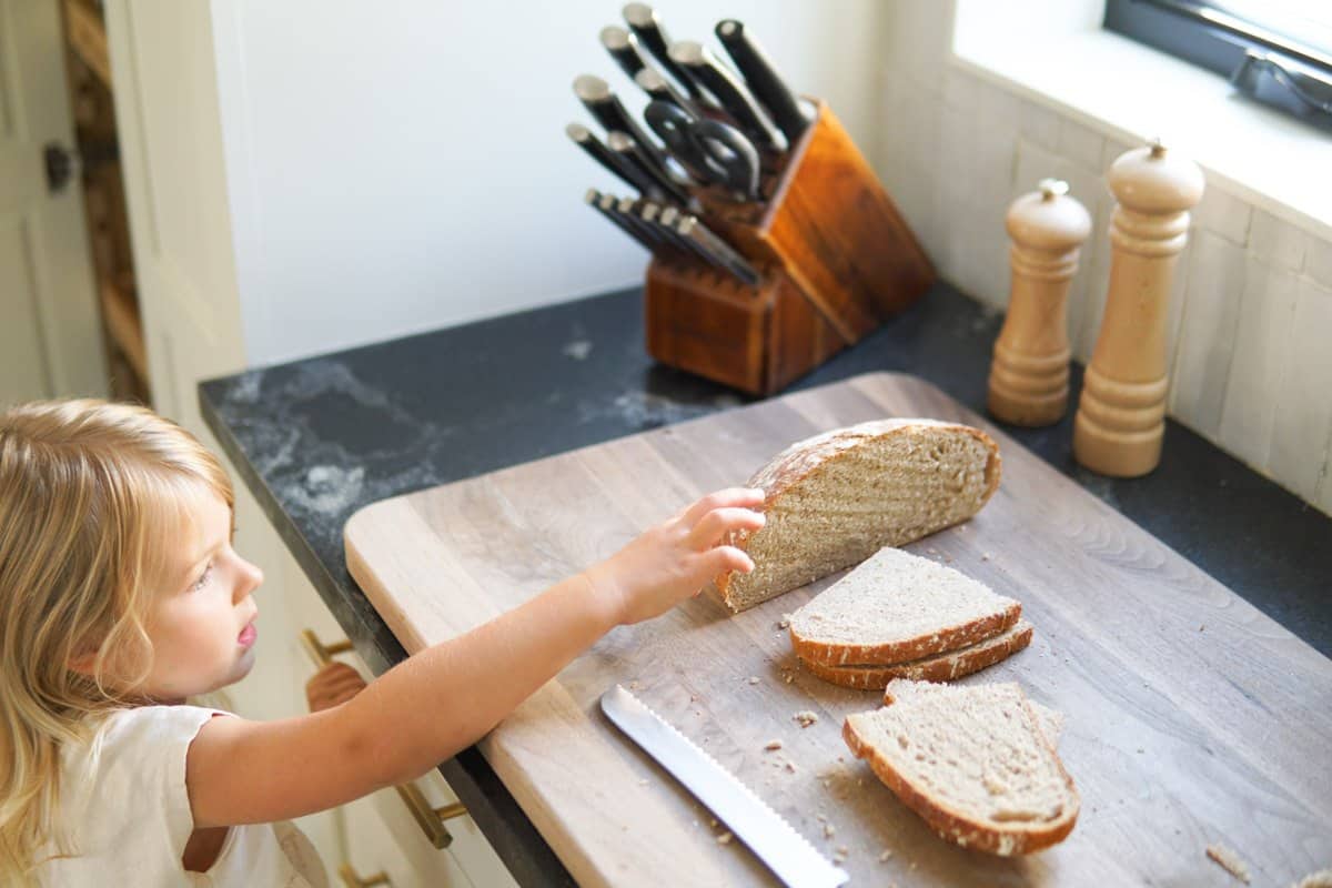 child grabbing a piece of bread from the counter