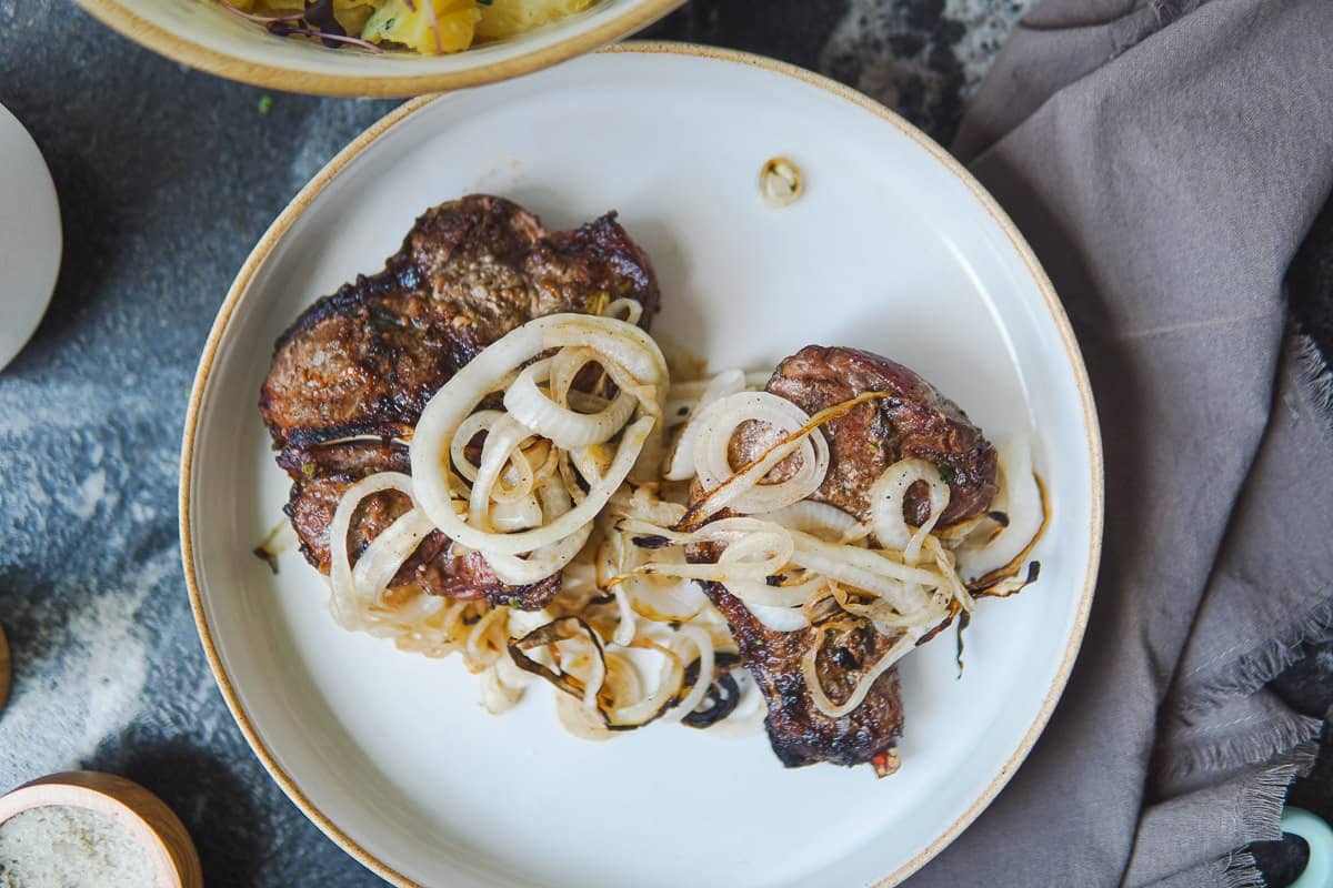 plate with two pork chops covered with grilled onions