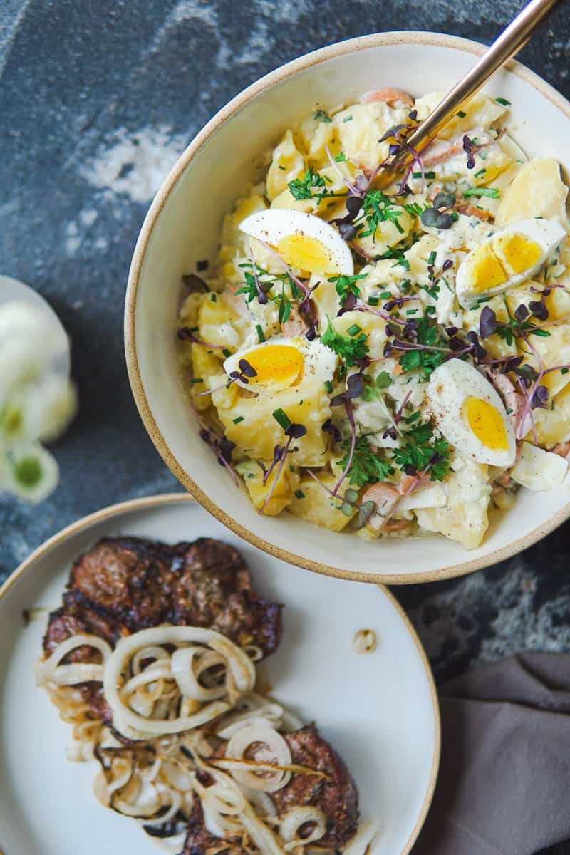 pork chops on a plate and a bowl of German potato salad