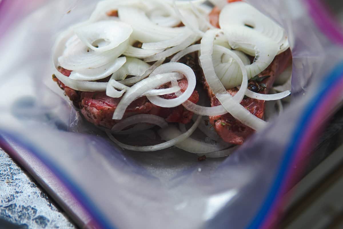 pork chops marinating in plastic bag with onions