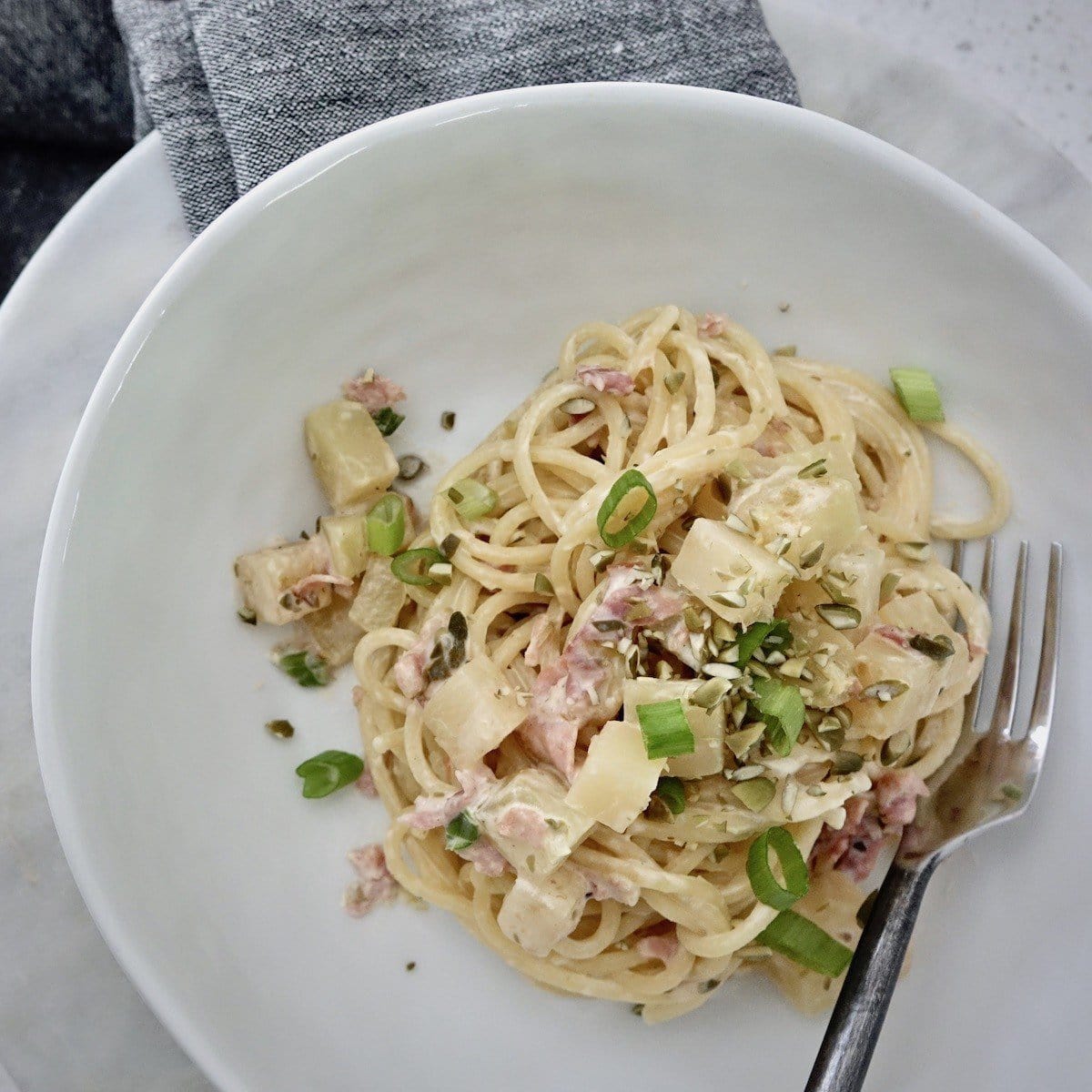 Kohlrabi Spaghetti served in a bowl with green onions and chopped pumpkin seeds