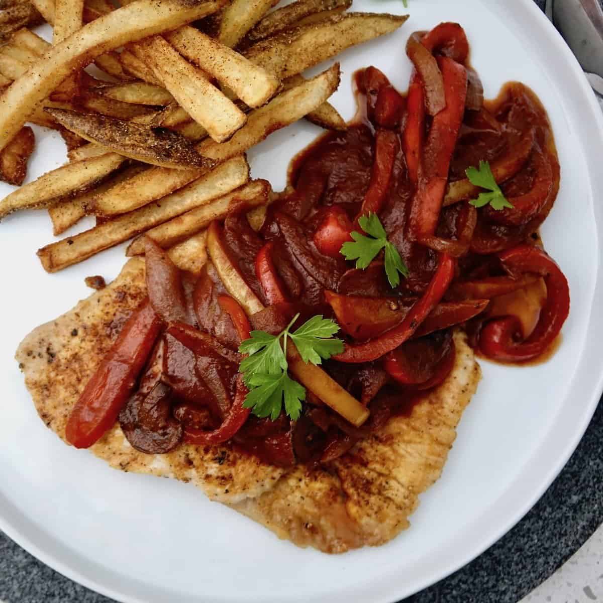 Zigeunerschnitzel on a round plate with potato fries