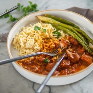 plate of German pork goulash with egg noodles and asparagus