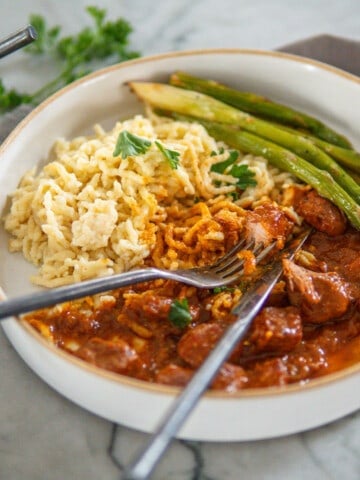 plate of German pork goulash with egg noodles and asparagus