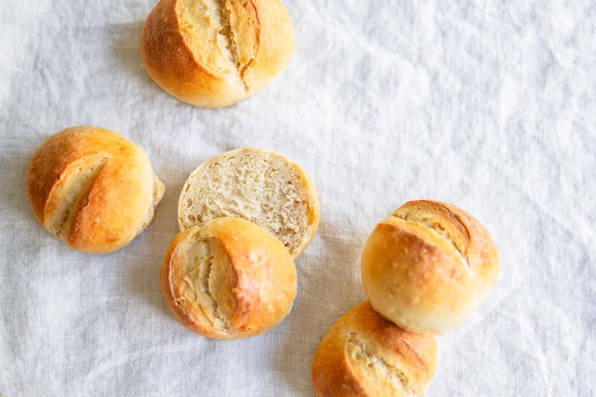 Crusty white rolls on a white linen tablecloth.