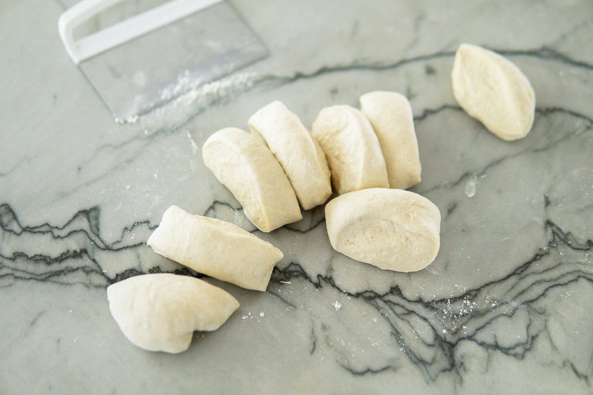 Cutting bread dough into 8 pieces to shape rolls.