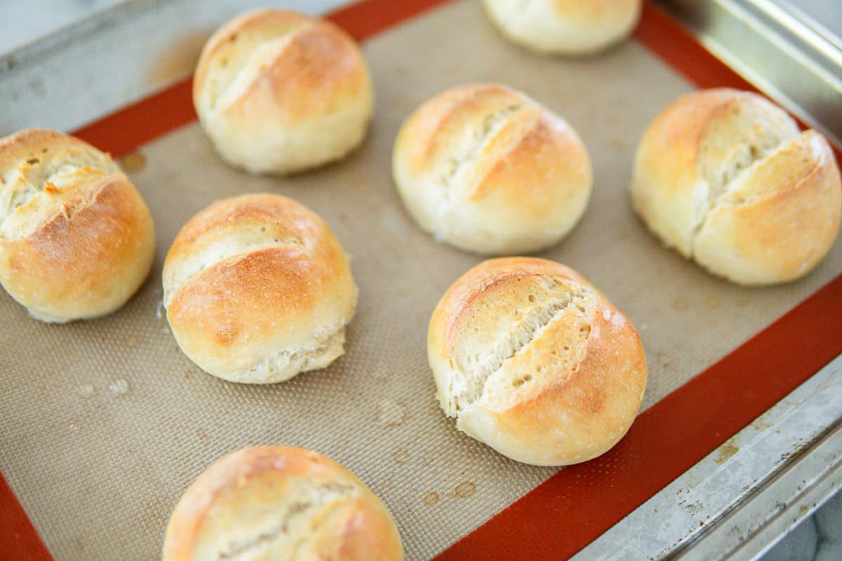 Baked crusty rolls on a baking sheet.