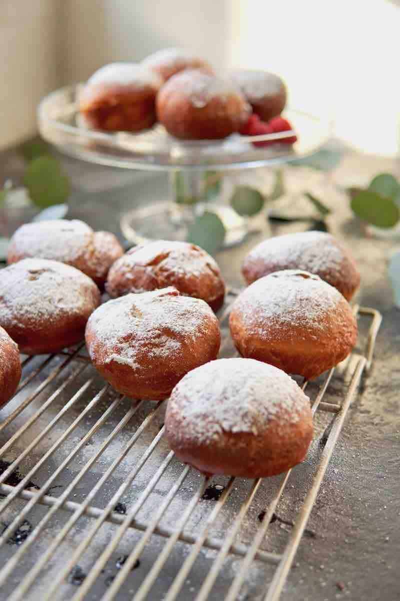 freshly powdered sugar coated donuts on a wire rack
