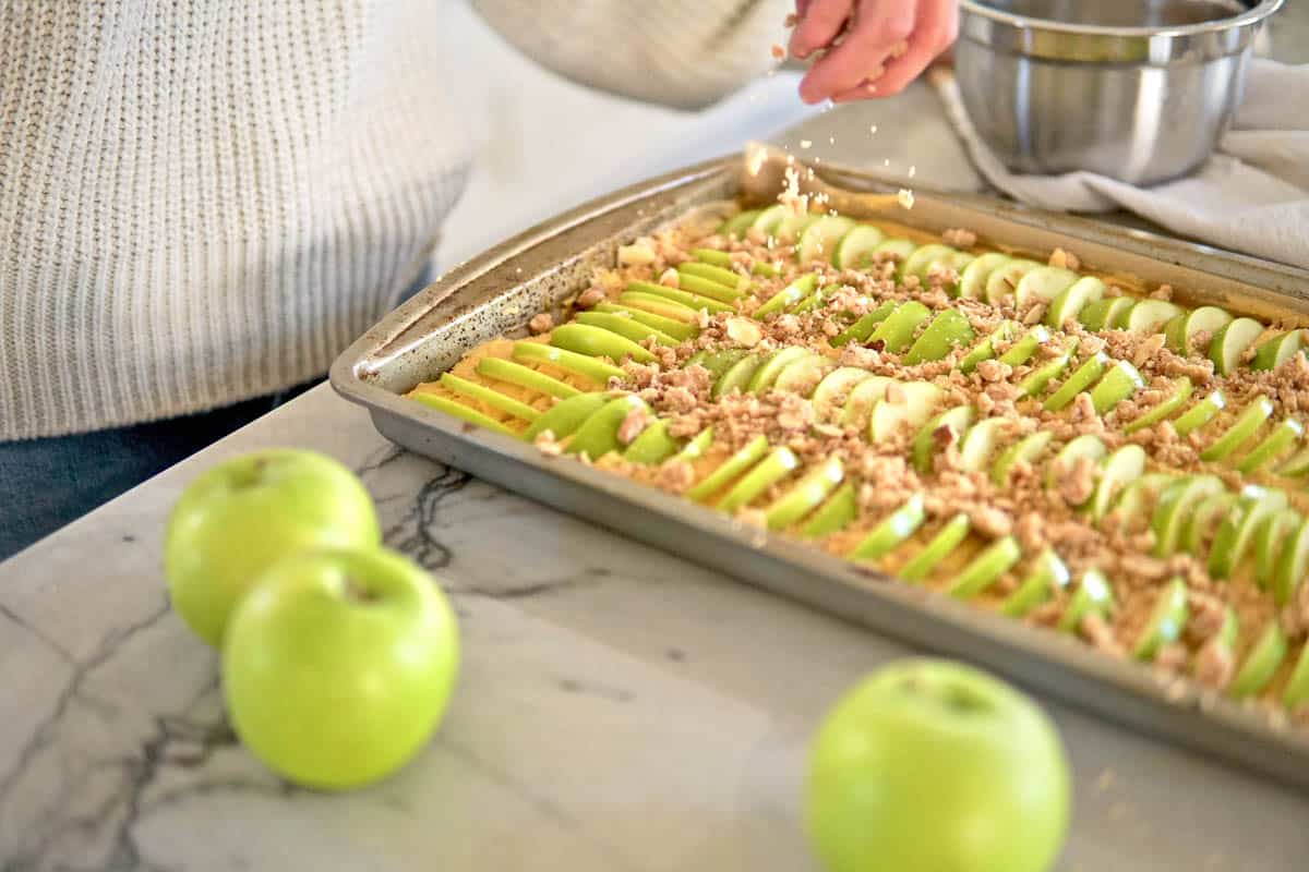 sprinkling streusel onto apple cake