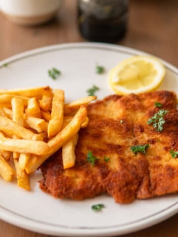 German pork schnitzel on a plate with fries and lemon
