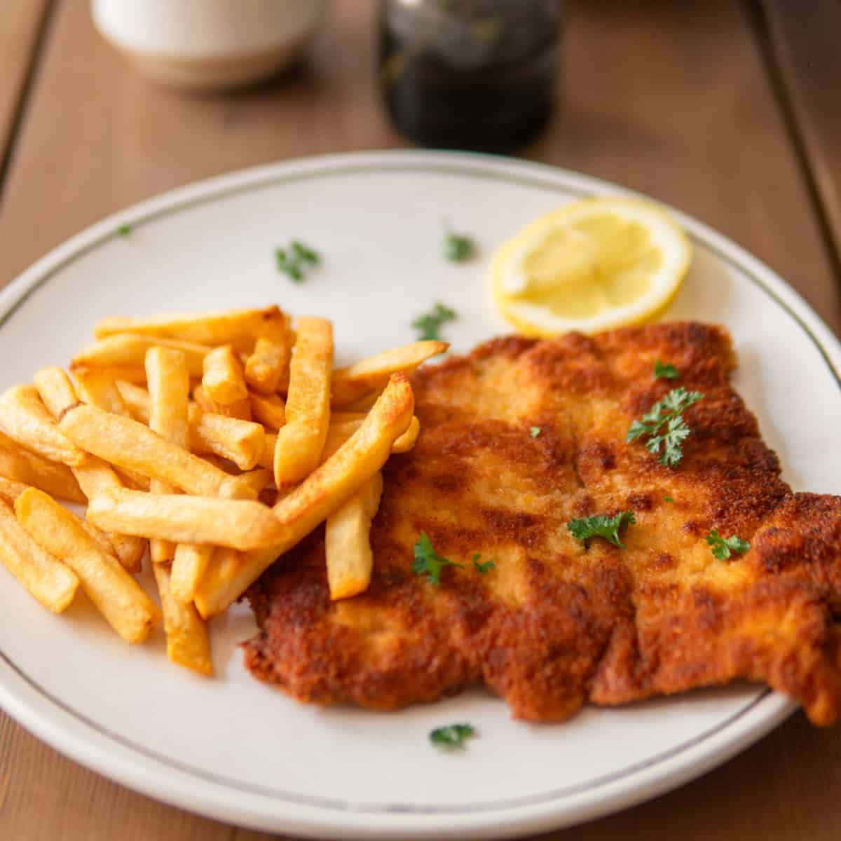 German pork schnitzel on a plate with fries and lemon