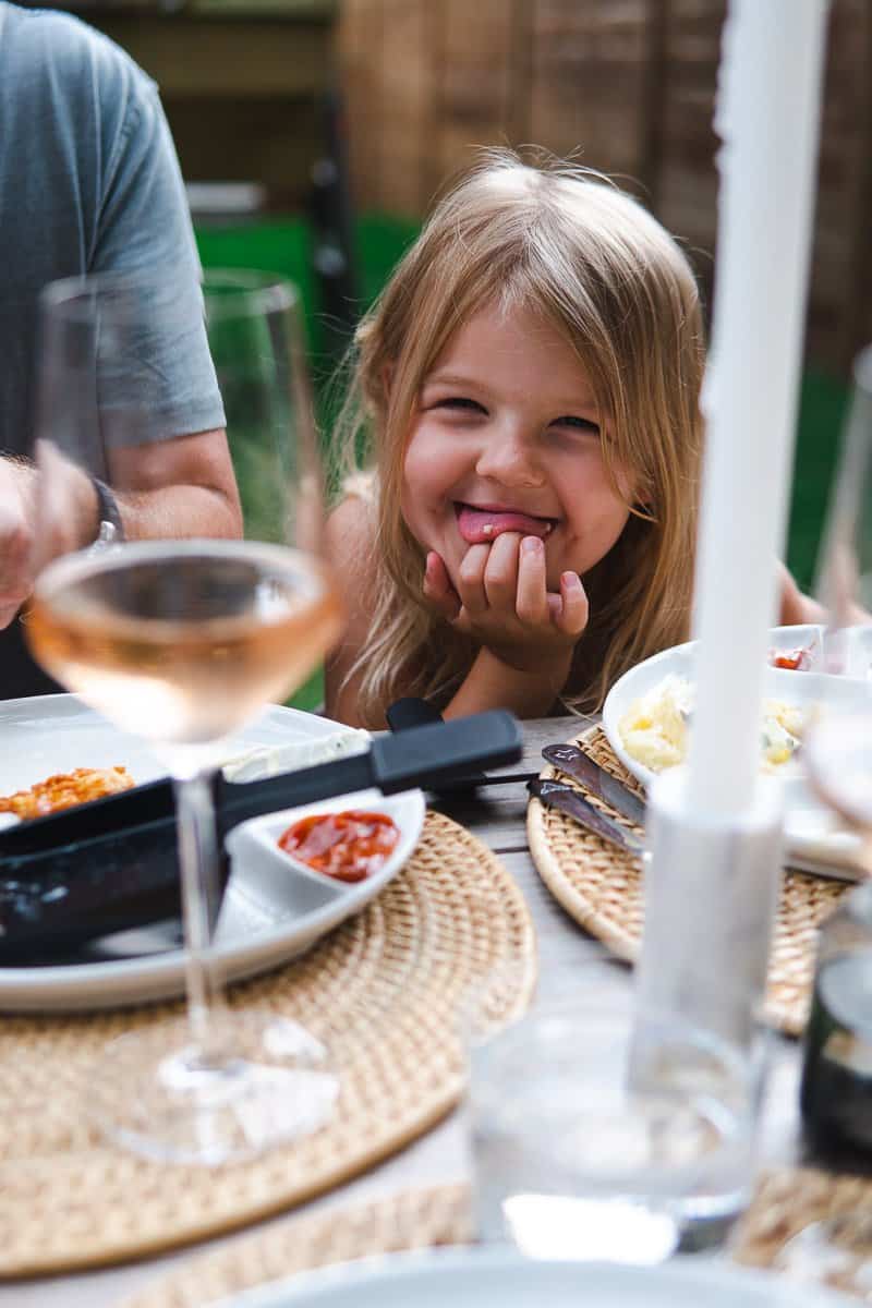 child smiling between plates filled with raclette