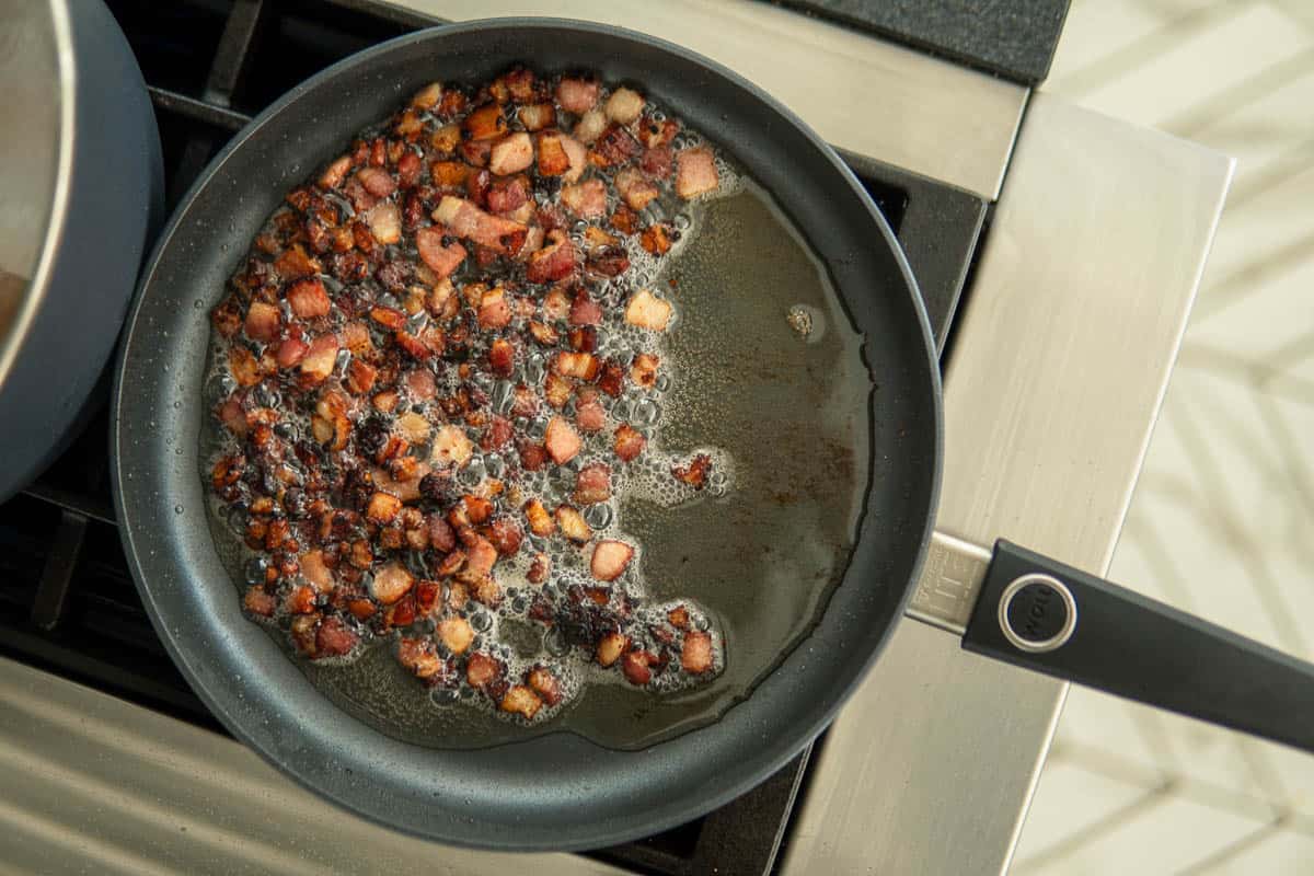 bacon pieces cooking in a sauté pan