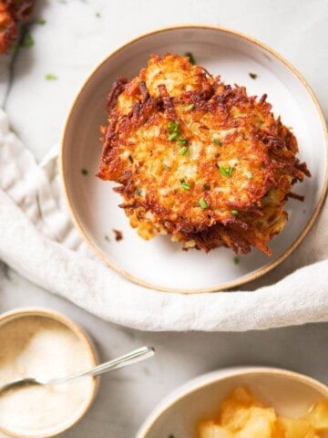 potato pancakes on a white plate with applesauce