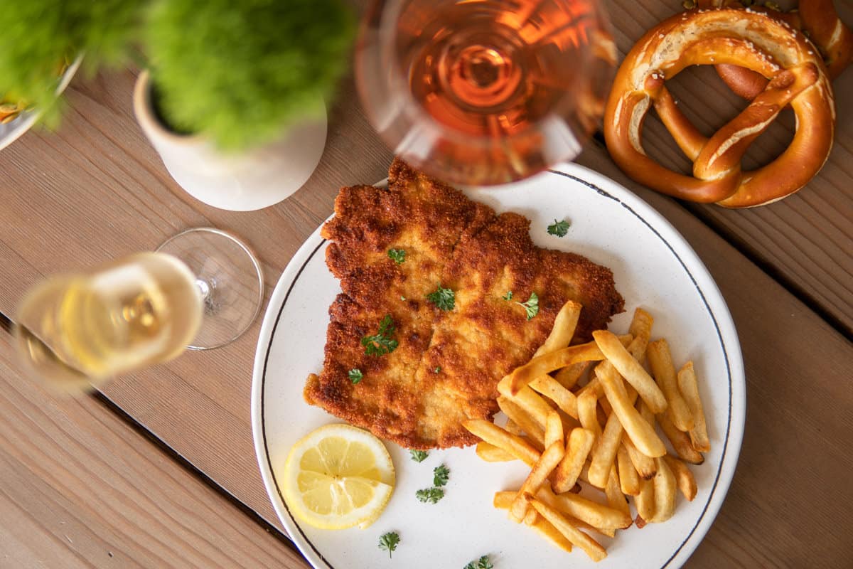 schnitzel and fries on a plate surrounded by glasses of wine