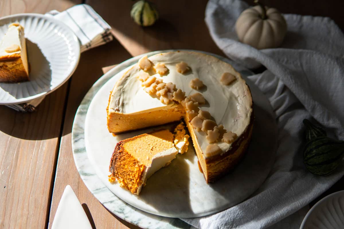whole pumpkin cheesecake with a slice laying on its side