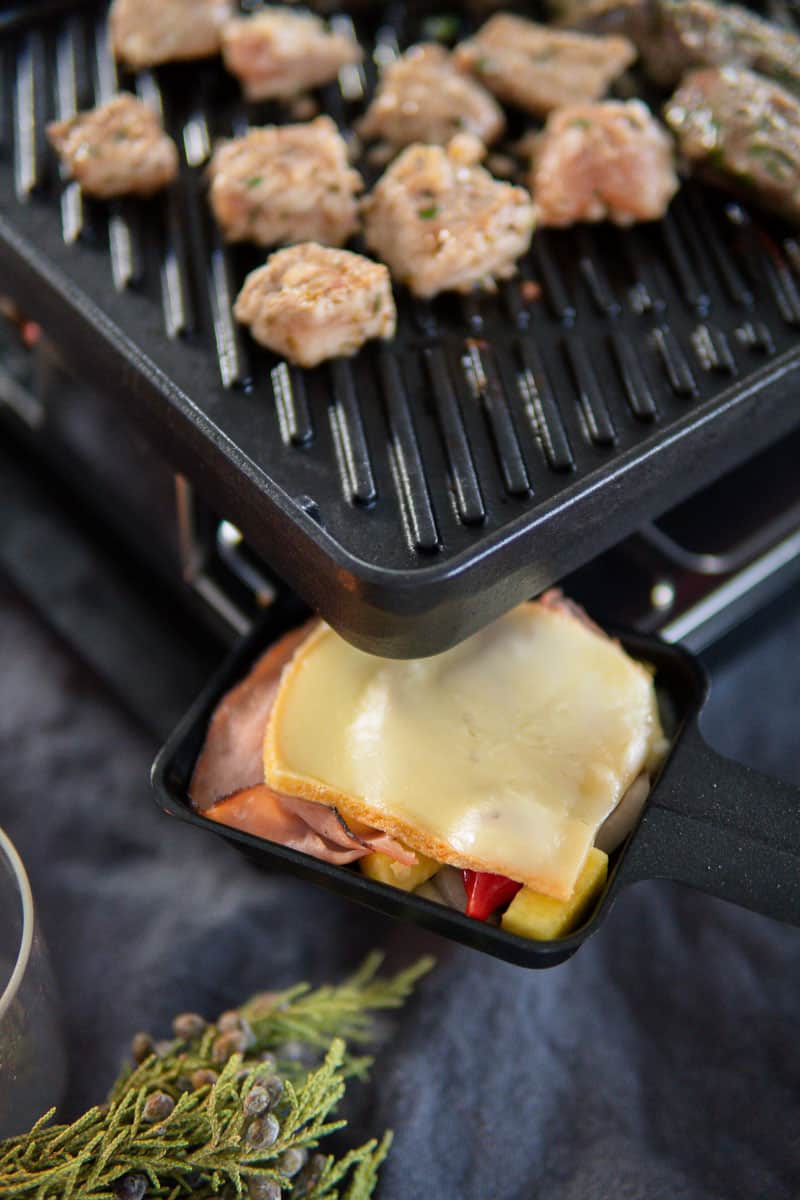 raclette cheese melting in pan and grilling meat on the raclette grill