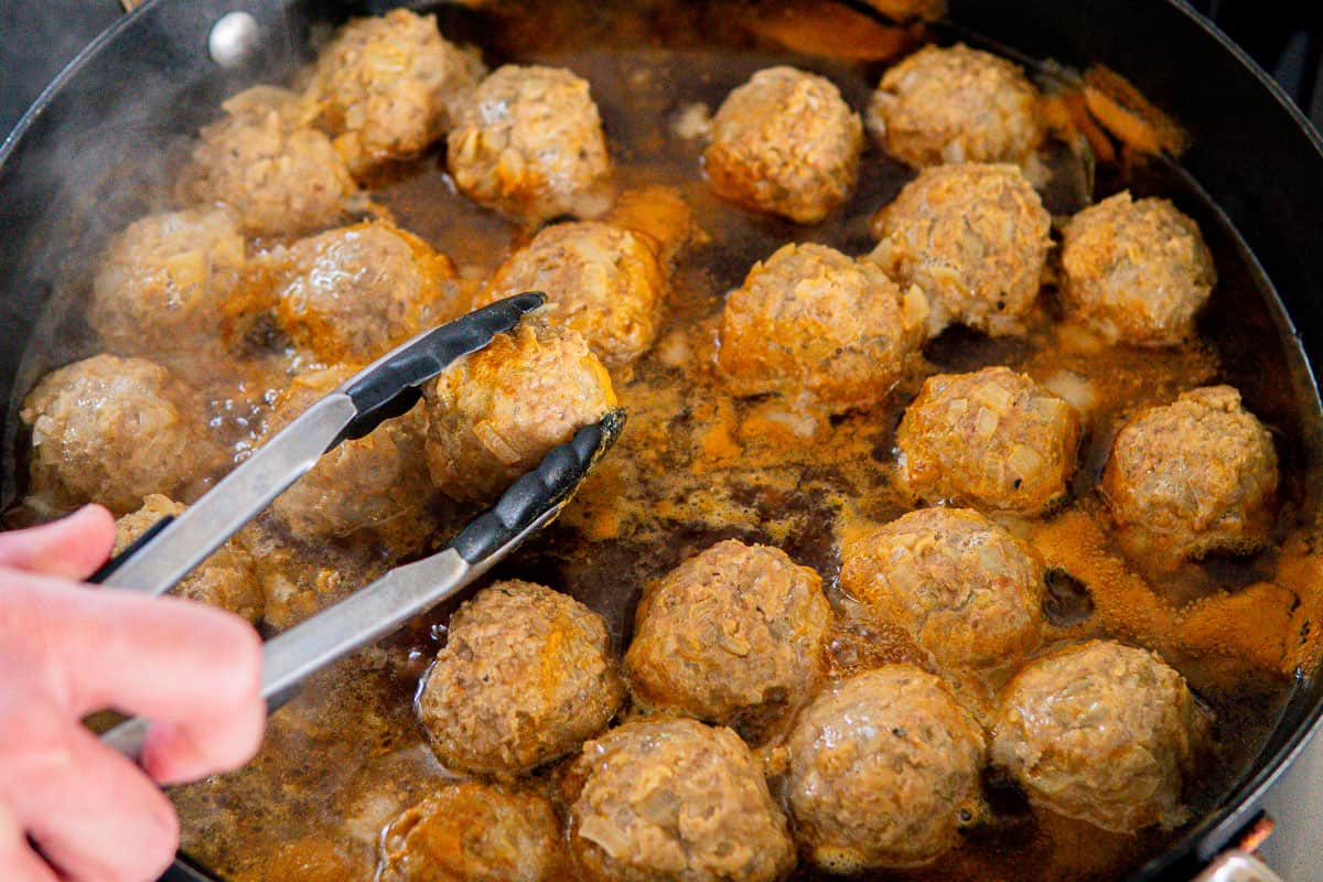turning over meatballs while simmering in beef broth