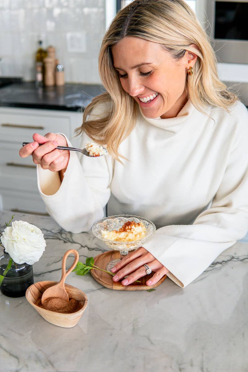 girl in white sweater eating homemade rice pudding topped with cinnamon sugar