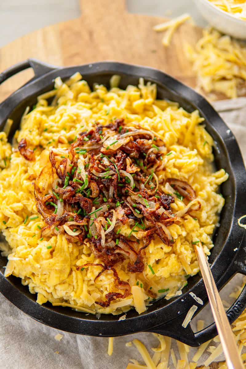 closeup of käsespätzle topped with caramelized onions and chives