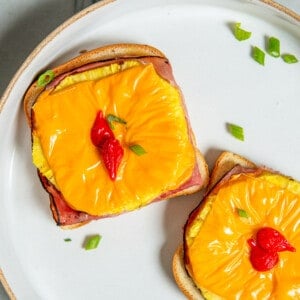 toast Hawaii on a white plate, garnished with green onions.