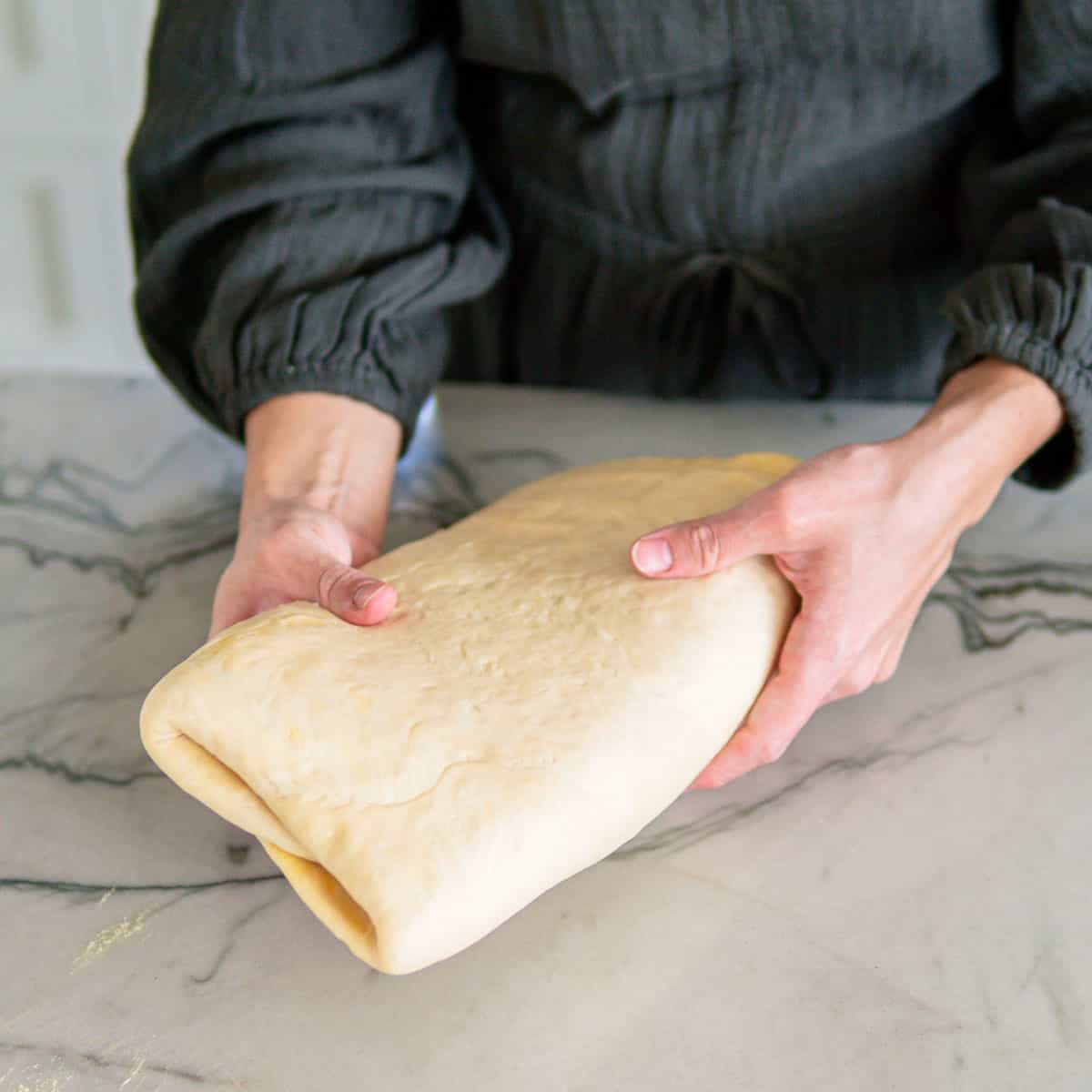 woman holding German croissant dough ready to be rolled out