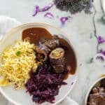 beef rouladen on a plate with noodles and red cabbage