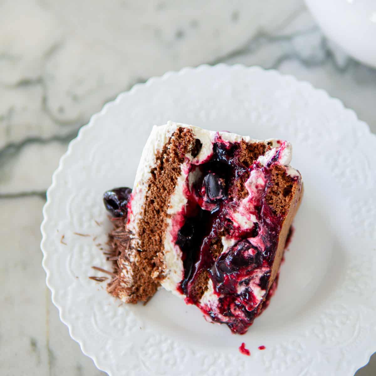 a slice of Black Forest cake laying sideways on a white plate