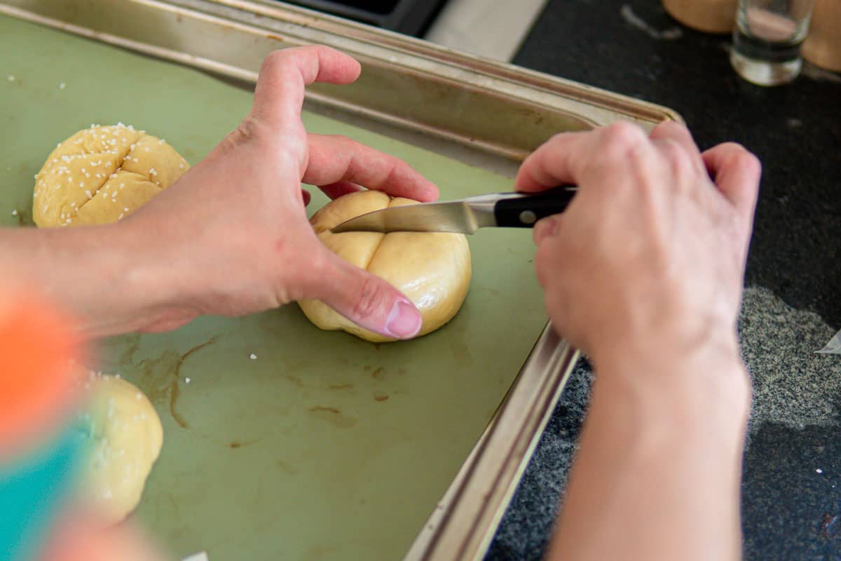 cutting a cross in the rolls before baking