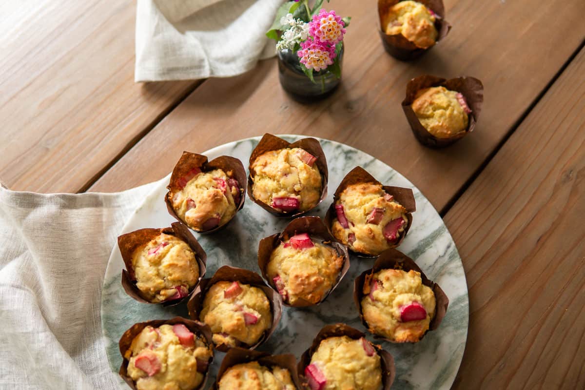 rhubarb muffins on a platter with more muffins scattered around