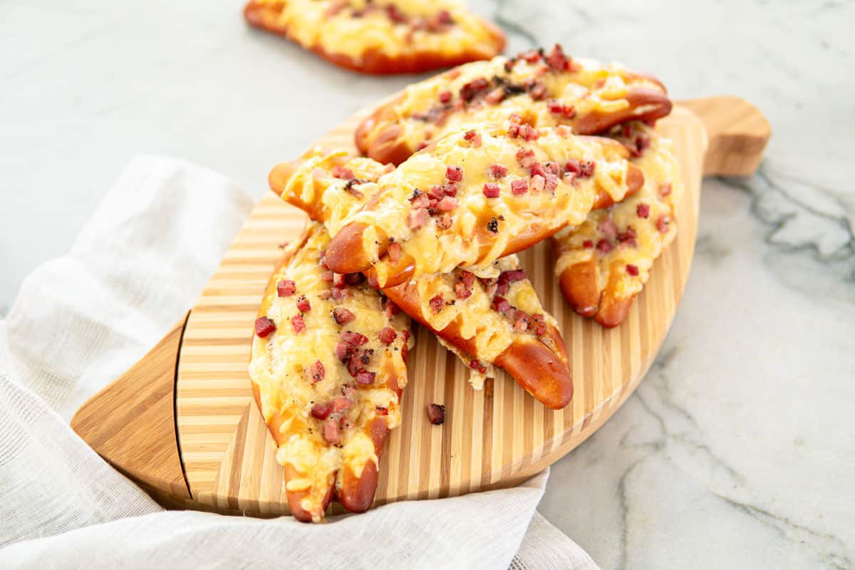 baked pretzels topped with cheese and bacon on a wooden board