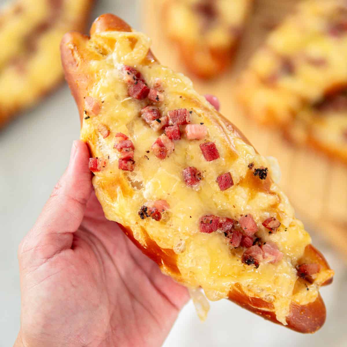 holding a soft baked pretzels with bacon and cheese