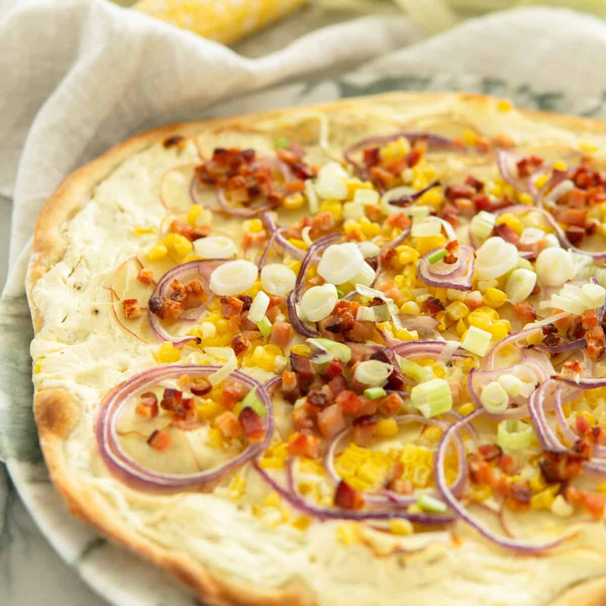baked summer flamnkuchen topped with corn, bacon, potato and onion