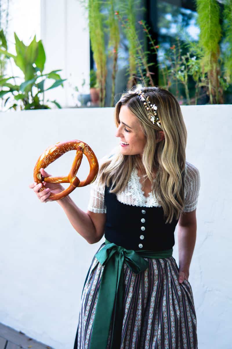 girl in a dirndl dress holding an Oktoberfest pretzel