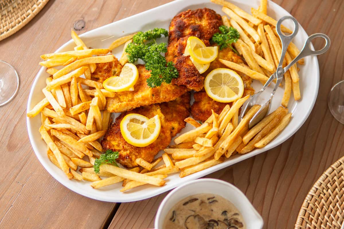 schnitzel on a platter with fries and jagerschnitzel sauce