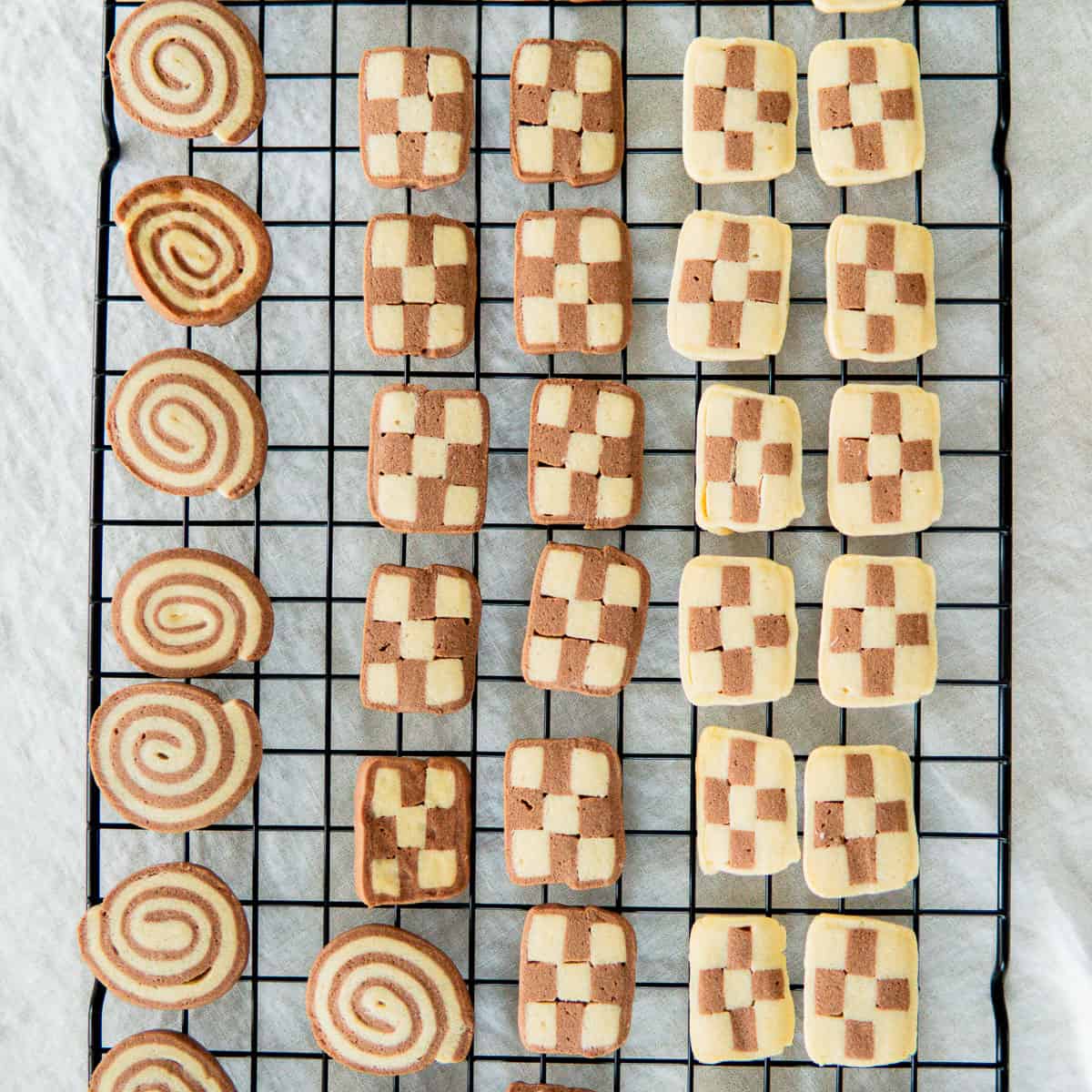 baked pinwheel and checkerboard cookies on a cooling rack