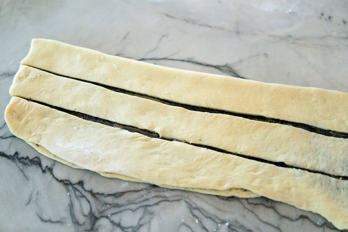 Filled dough cut into three strips and ready for braiding.