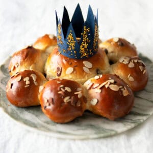 Dreikönigskuchen on a platter and topped with a paper crown.