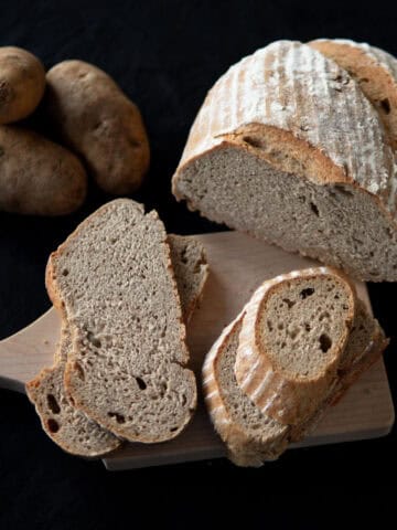 Sliced sourdough potato bread sitting on a wooden board.