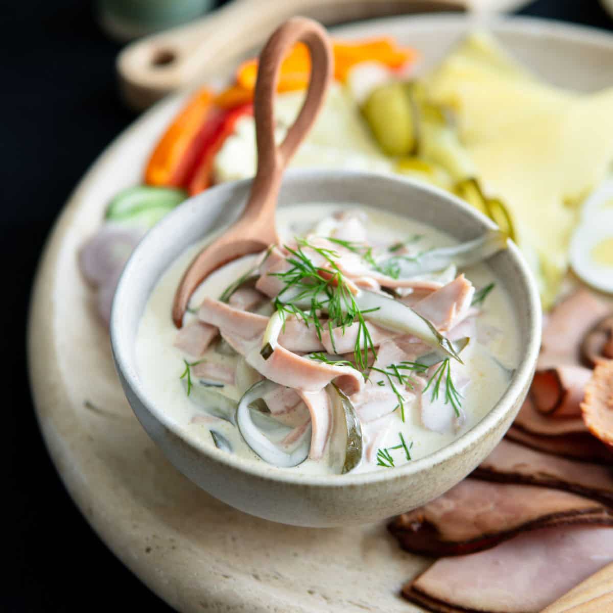 German bologna salad in a bowl next to a charcuterie and cheese plate for a traditional German dinner.
