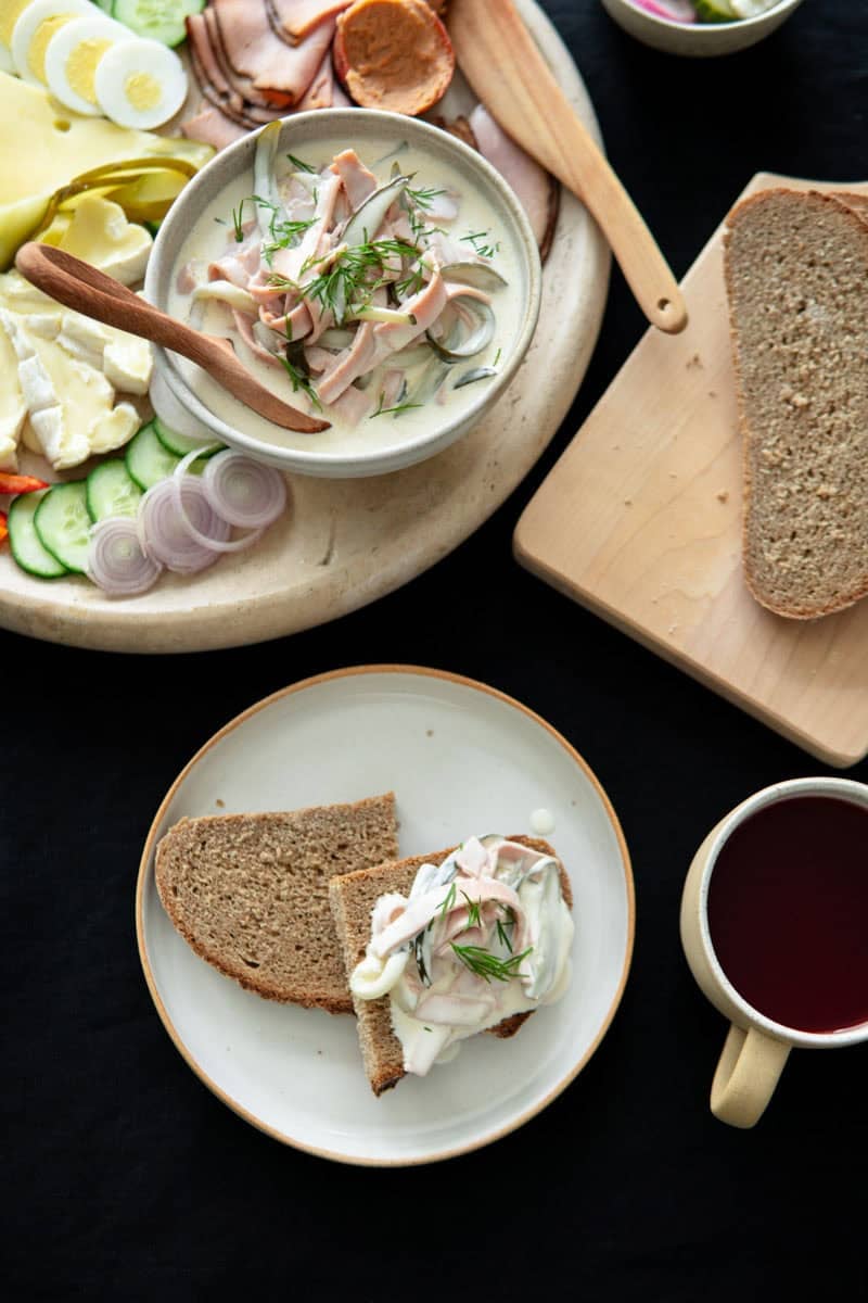 German bologna salad in a bowl next to a charcuterie and cheese plate for a traditional German dinner.