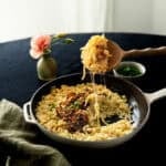 a cast iron dish filled with kaesespaetzle and topped with caramelized onion and chives