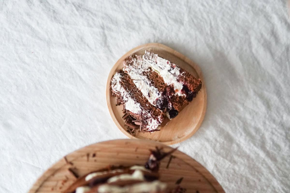 A slice of German Black Forest cake sitting on a wooden plate.